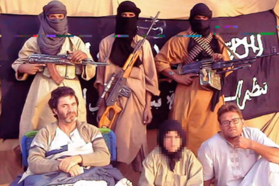 Fotograma de un video de Al Qaeda en el Magreb Islámico (AQMI) que muestra a los tres cooperantes españoles secuestrados en 2009 custodiados por tres hombres armados y encapuchados en el desierto.