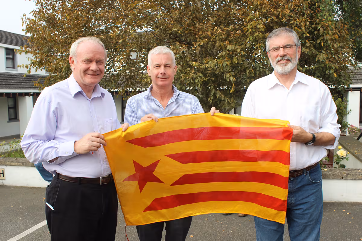 Martin McGuinness, Seán Crowe y Gerry Adams de Sinn Féin en 2014 sosteniendo una Estelada roja, bandera que representa a Cataluña, cuya independencia apoyan.