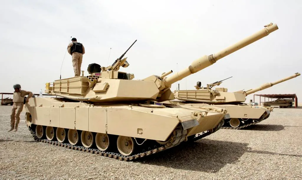 Un soldado Iraquí encima de un tanque Abrams M1A1 mientras otro salta al suelo en la base militar conjunta Iraquí-estadounidense de Basmaya el 15 de marzo de 2010. Créditos: AFP